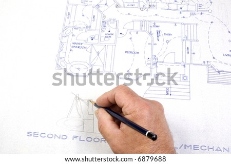 Contractor making changes to a set of building plans for a custom house with draughting tools