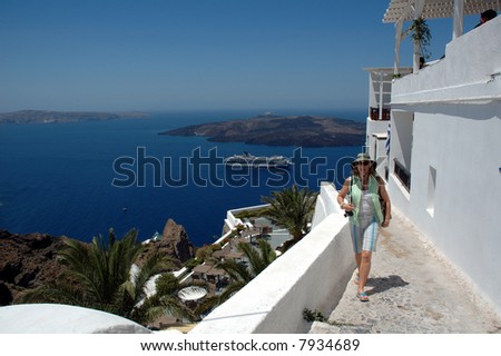 An older woman american tourist walking the streets of Santorini a Greek island in the Mediterranean sea with the cruise ship anchored in the caldera