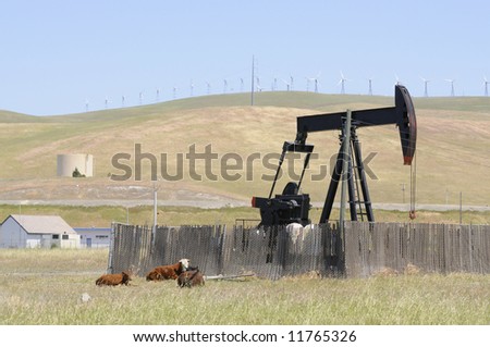 Oil well pump with wind generators in the background, showing old and new technology, or renewable and non renewable resources in northern California