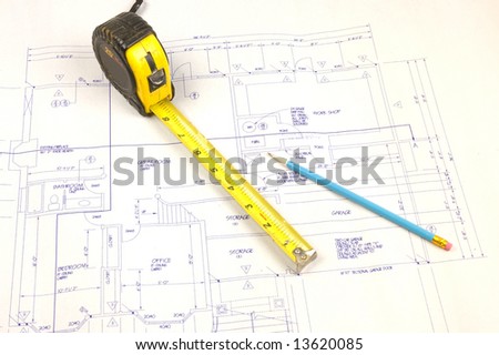 Set of building plans for a custom house with tape measure and pencil