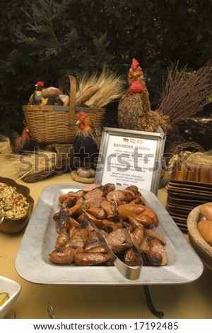 Bavarian station at an international food party, with sausage, bread, chickens, and corn