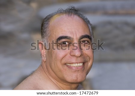 smiling middle-aged Iranian man looking over shoulder in closeup