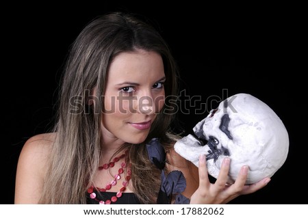 Beautiful young brunette woman holding skull and a black rose with an evil smile for halloween