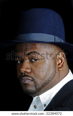 young bearded African American man in a fedora isolated on a black background