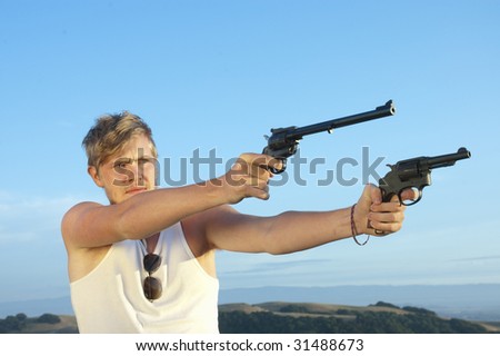 young man in tee shirt and pistols pointed at target