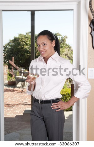 Beautiful African-American woman holding a glass of white wine while standing at a window