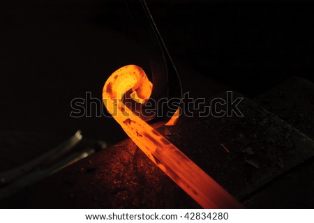Blacksmith working on decorative handrail bending the heated metal