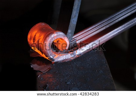 Blacksmith working on decorative handrail bending the heated metal