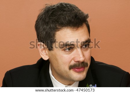 Groom at a wedding looking very intent over a colored background