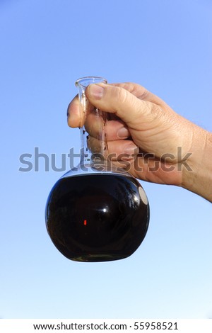 chemical engineer, doctor or research scientist holding a sample of oil in a flask