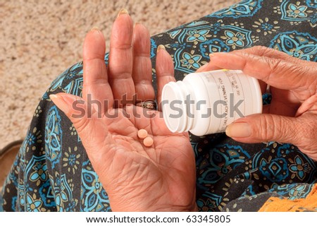 Elderly African American woman pouring her pills from a container into her hand