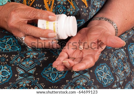 Closeup of an Elderly African American woman pouring pills from a bottle into her hand