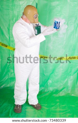 Man in Hazmat clothing in decontamination chamber wearing a gas mask and carrying toxic chemical that is exuding gaseous vapor