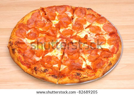 whole Pepperoni pizza on a pan sitting on a table in closeup