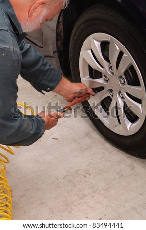 Mechanic using a air pressure gage/inflation tool while rotating the tires on a vehicle