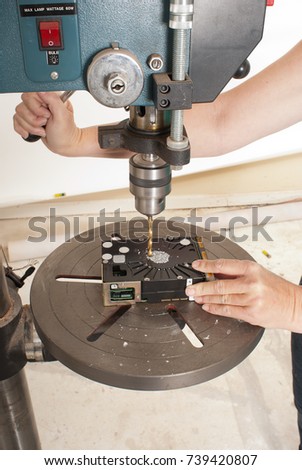 Technician destroying data on a hard drive by drilling through the platters with a Drill Press or a electric hand drill