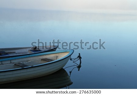 Lake in denmark with boats and fog dissipating at the horizon