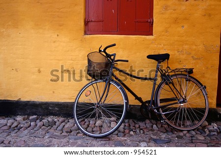 in the street of a danish village in grenaa in the summer a bike against a yellow wall