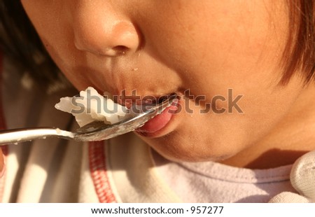 half face of child eating rice with a spoon