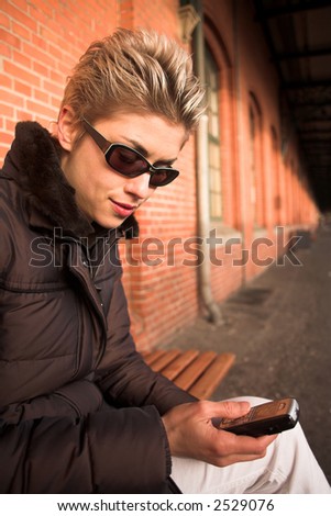 pretty woman outdoor in an old village in denmark with a wall   in red brick and mobile phone in hands