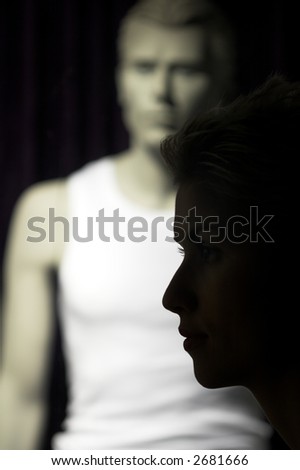 nightlife : woman outdoor in a  city  on shopping tour,  profile of her passing by a shop with man model