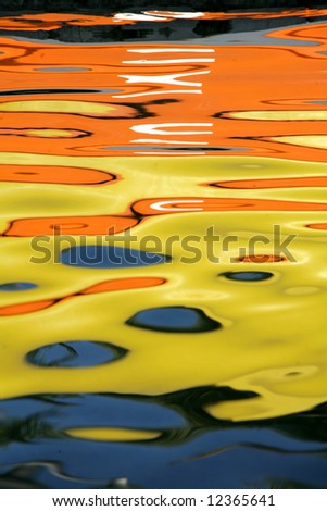water  reflection of a child playing at the edge of a water surface fronting a colorful wall