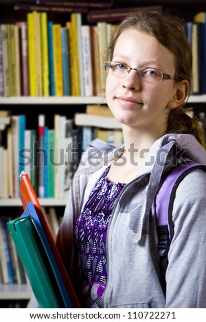 Young girl standing near the bookshelf