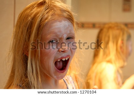 Little girl making faces in front of  a mirror in golden-orange light