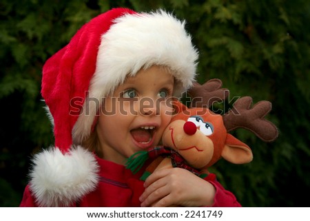 Portrait of a baby girl wearing Santa Claus hat with reindeer toy
