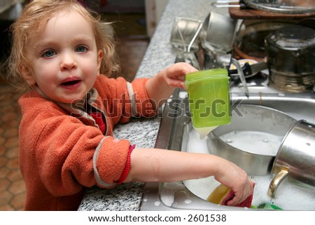 Little baby washing the dishes in the kitchen