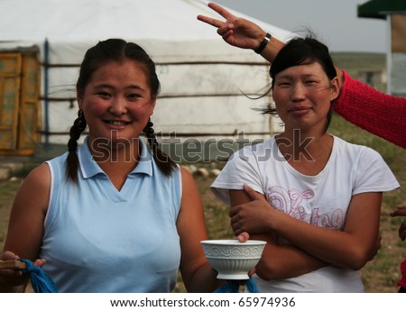 CAMP NEAR KHORGO VOLCANO, MONGOLIA - AUG 7: nomadic young women welcome tourists in a camp near khorgo volcano in Mongolia during summer, August 7,  2008. They offer milk on August 7, 2008 in a camp.