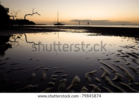 Sand patterns in tidal flat and sailboat at sunset, Florida