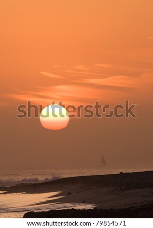 Sunset over Pacific Ocean, sailboat on horizon