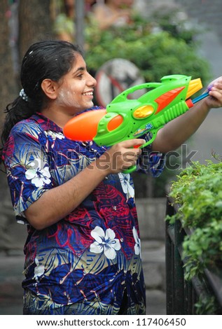BANGKOK, THAILAND - APRIL 13: A Woman sprays Bangkok residents and tourists with water from a toy water gun during the annual Songkran New Year water festival on April 13, 2008 in Bangkok.