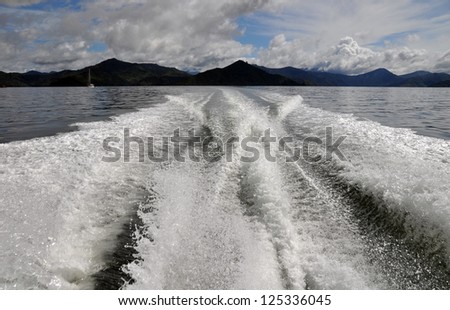 Cruising the Marlborough Sounds, New Zealand. In the foreground is a motor boat wake and in the background are the hills of Queen Charlotte Sound.