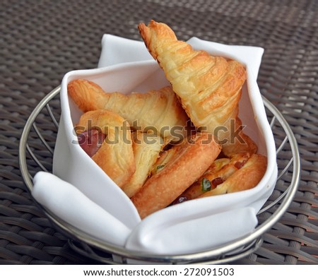Basket of freshly baked pastries including Croissants and Pain aux Raisins wrapped in a white cloth