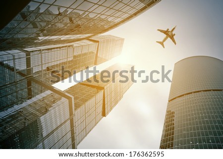 Photo of an airplane above the glass office buildings