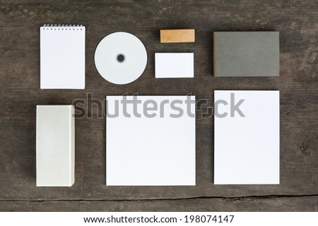 Blank stationery set on wood background: business cards, booklet, sheets, notebook, stamp, CD, and boxes