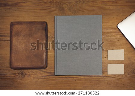 Blank leather case for tablet (for the application logo), book cover (booklet), and business cards on a wooden texture. Vintage style
