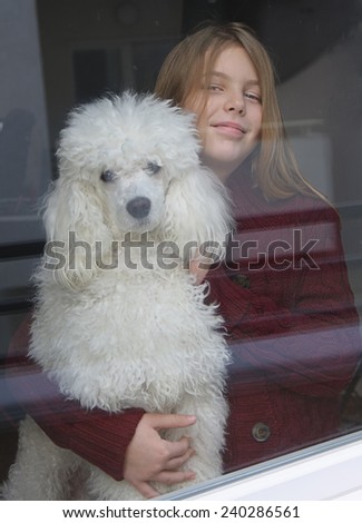Little girl and her dog looking out the window