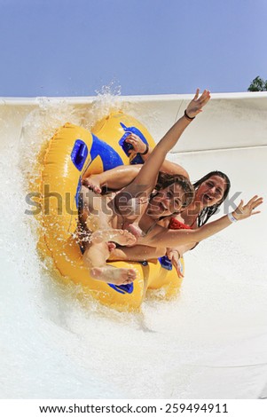 Rhodes, Greece-August 21,2014:Two cheerful girls,smiling and with open arms , drive with tube on the water slide in the park Water