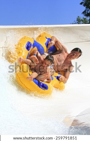 Faliraki,Rhodes, Greece-August 17,2014:Father and son drive with tube on the rafting slide in the  Water park.Rafting slide is one of many popular game for adults and children in Water park