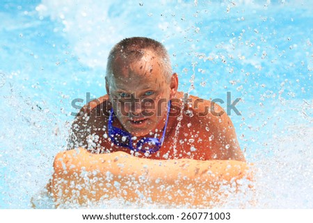 Faliraki,Rhodes,Greece-August,12,2015:Man on the mat racer slide in Water park,Mat racer slide is very popular for Youth and adults persons in the Water Park.