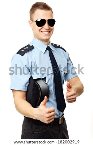 Young policeman standing holds police cap at hand and shows you fingers up