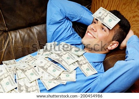 Young businessman lying on the couch and relaxes with money