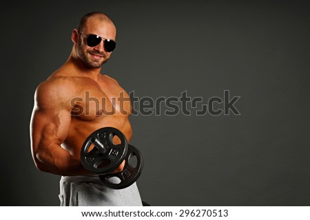 Muscular man exercises with dumbbell, right you can write some text
