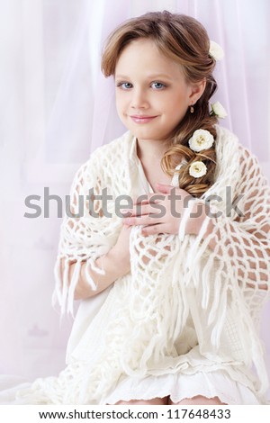 beautiful little girl with perfect makeup and hair-dress with flowers looking at you