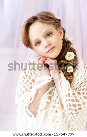 beautiful little girl with perfect makeup and hair-dress with flowers looking at you