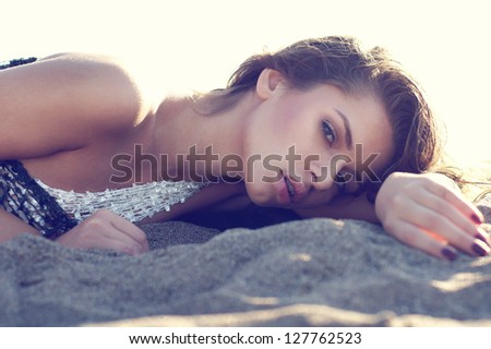 fashion face portrait of young beautiful woman lying at the sand of the beach