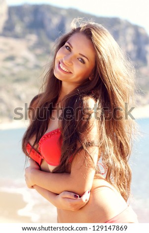 beautiful young smiling woman posing in red bikini at the beach